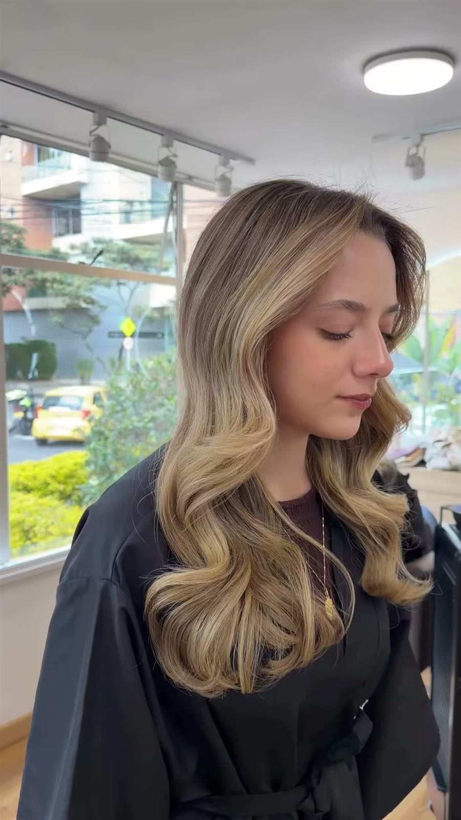 Perfil de una clienta con balayage rubio en ondas